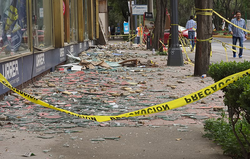 Photograph of caution tape in front of earthquake street damage. Wikimedia. 