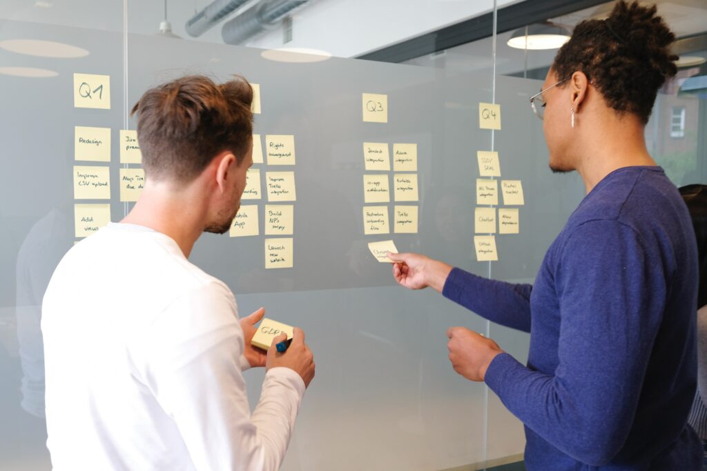 Two people looking at sticky notes on board. 