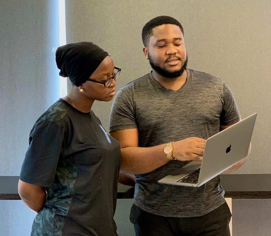 Man teaching woman something from computer.