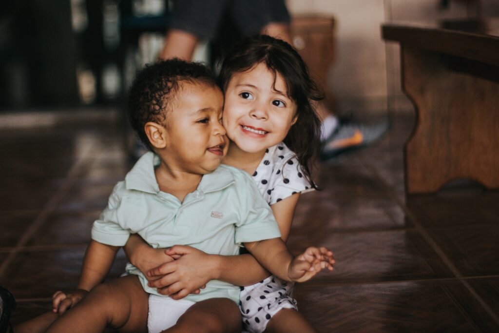 Todler siblings smiling and hugging. 