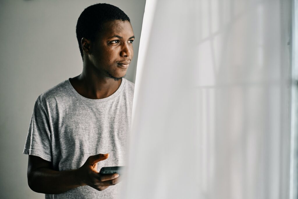 African American man looking outside a window. 